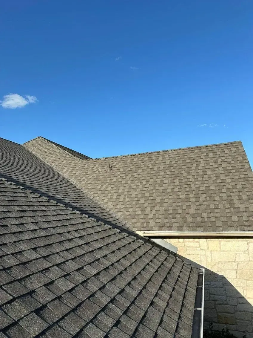 Gray asphalt shingle roof against a clear blue sky.