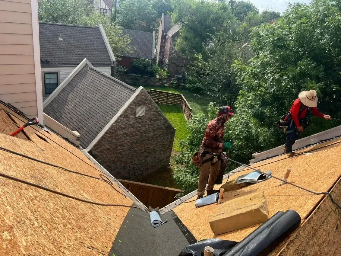 Two roofers working on a residential roof, wooden planks, sunny day.