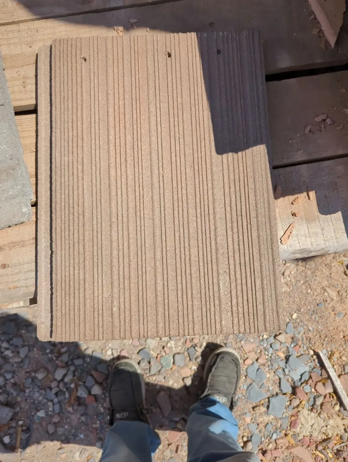 Person standing near a brown textured tile, outdoor setting.
