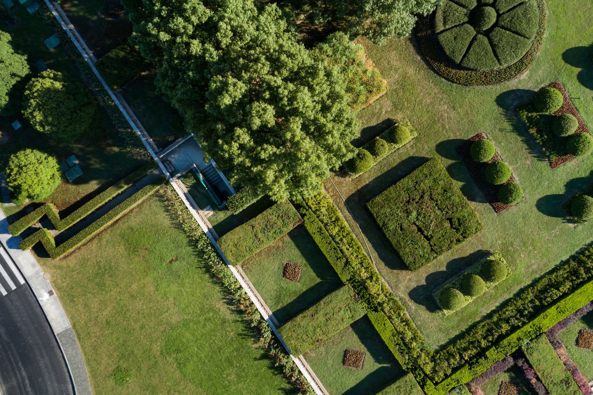 Aerial view of a landscaped garden with geometric hedges and trees.