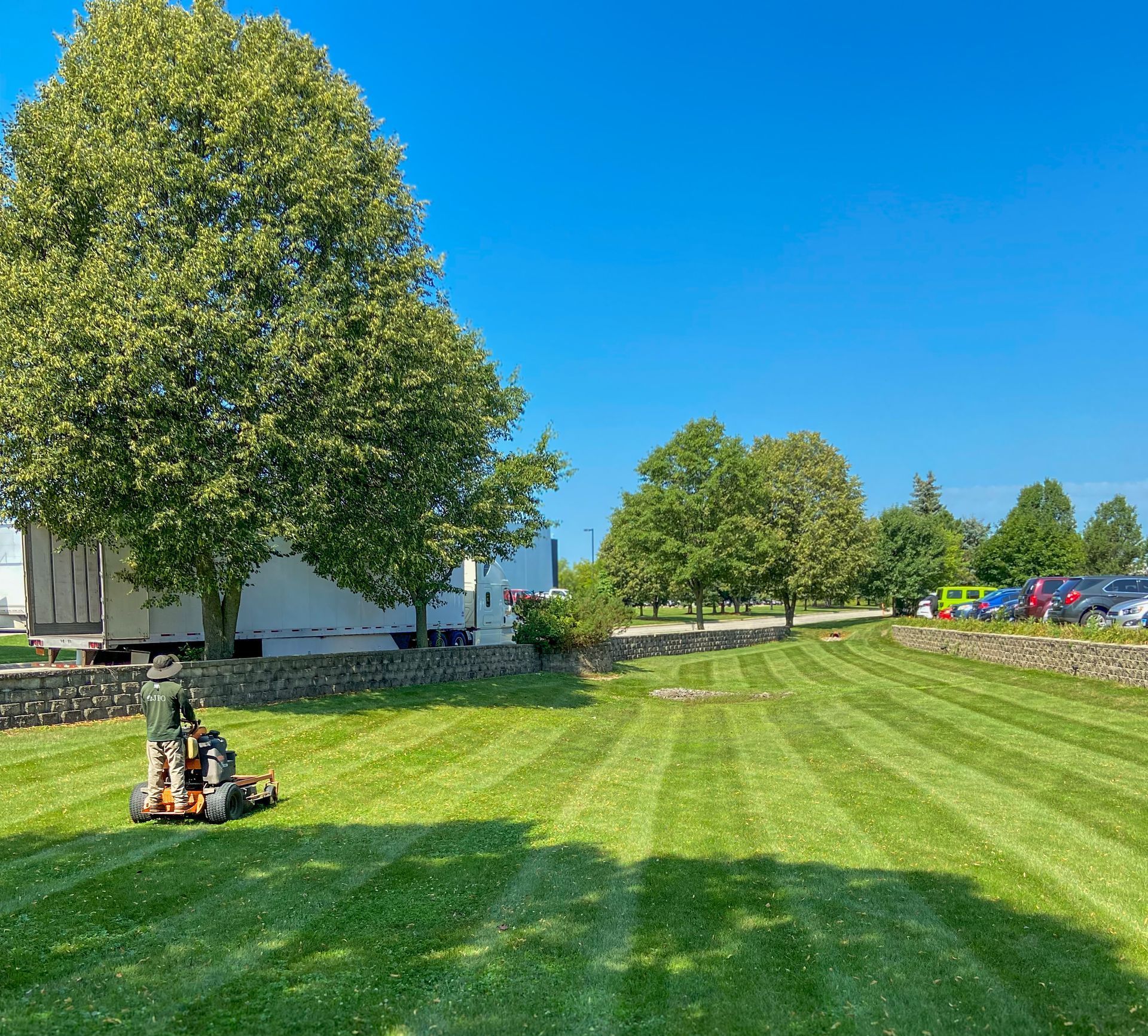A man is riding a lawn mower through a lush green field.