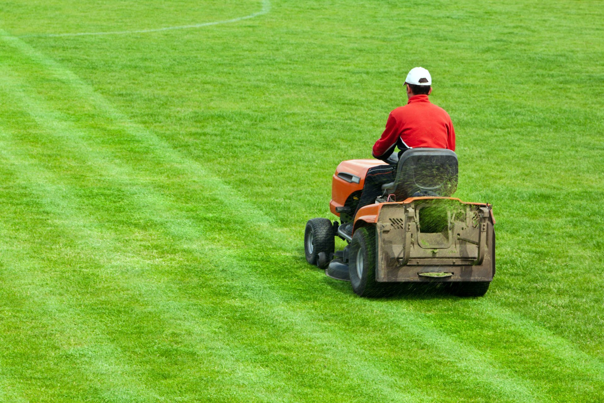 A person riding a lawn mower on a field a Lawn Care Treatment - West Chicago, IL - JBO Services