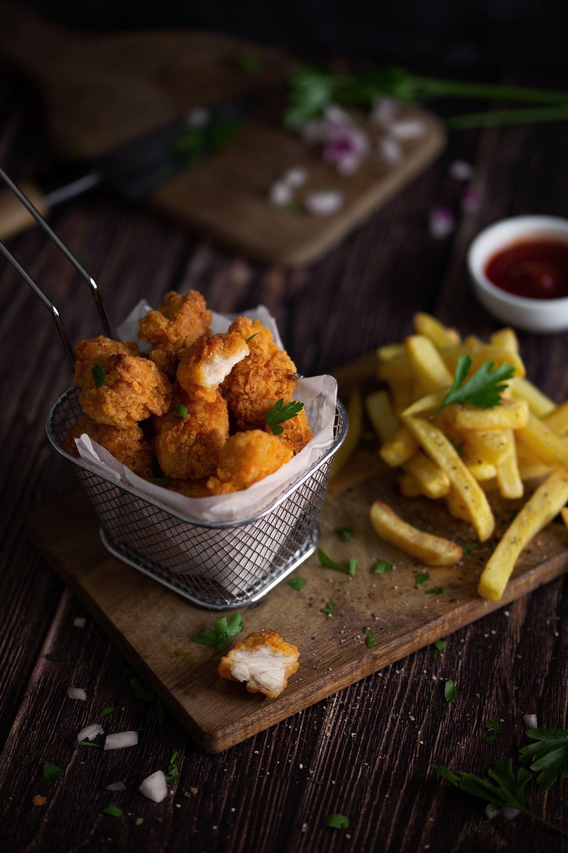 Un panier de poulet frit et de frites sur une planche à découper en bois.