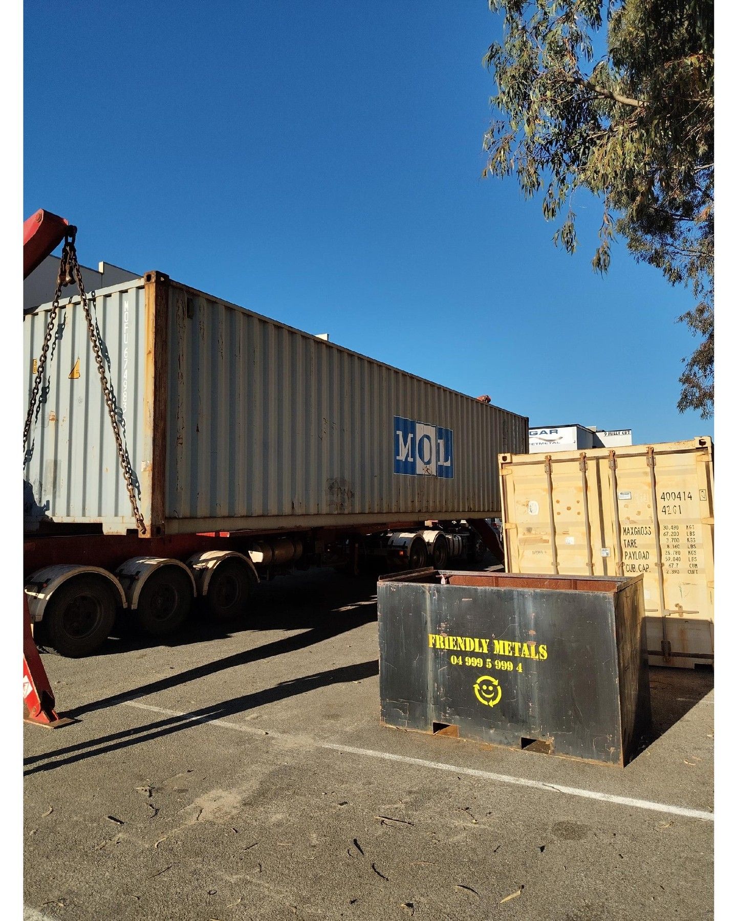 White, arched-roof structures with doors, framed by benches and trees. A central sculpture is in front.