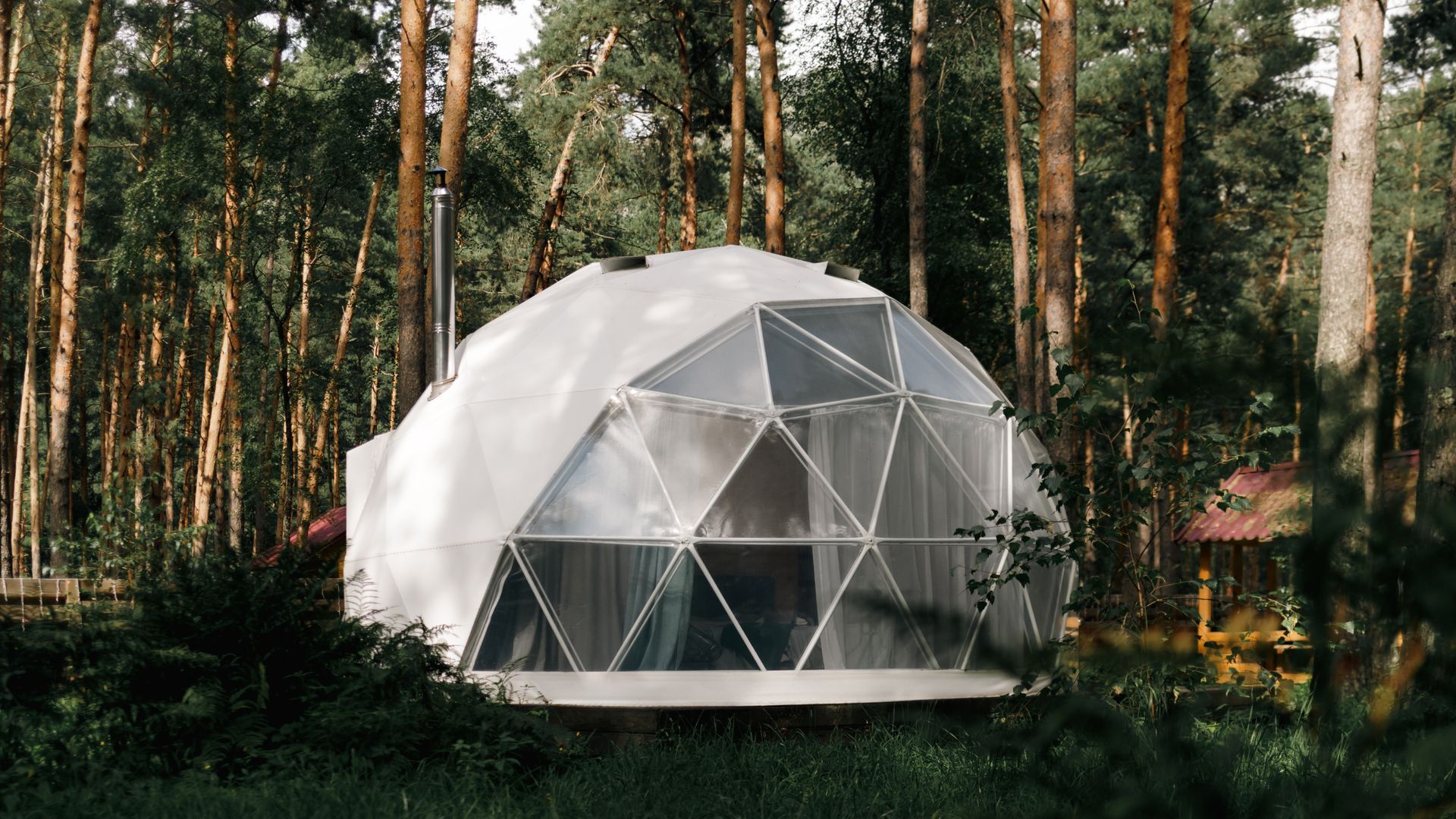 Geodesic dome home in a forest with trees and greenery; white and transparent panels. Geodesic dome home in a forest with trees and greenery; white and transparent panels.