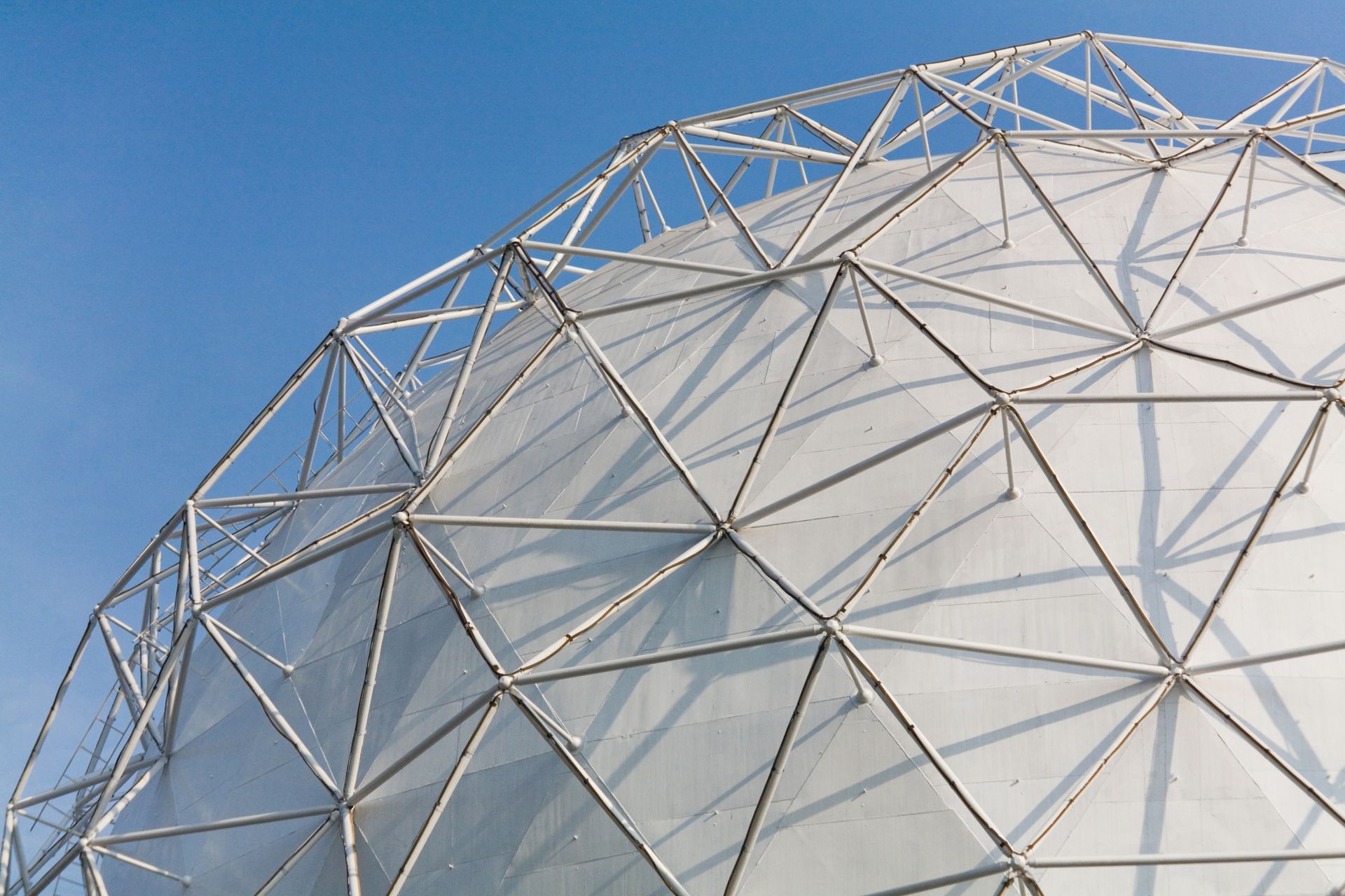 White geodesic dome against a clear blue sky.