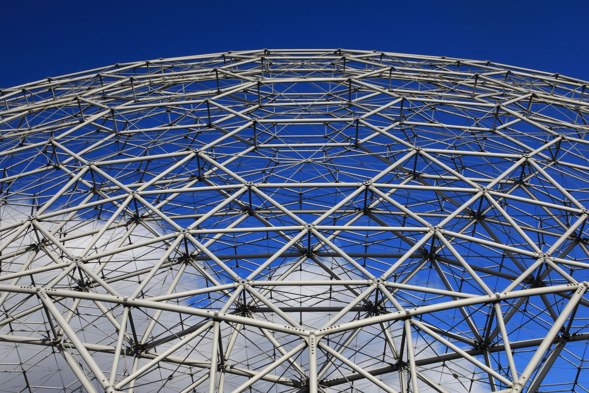 White metal geodesic dome against a blue sky with clouds.