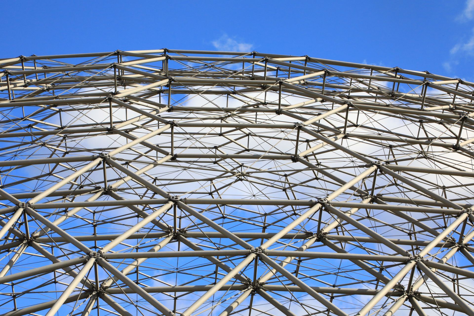 Steel geodesic dome against a blue sky with scattered clouds.