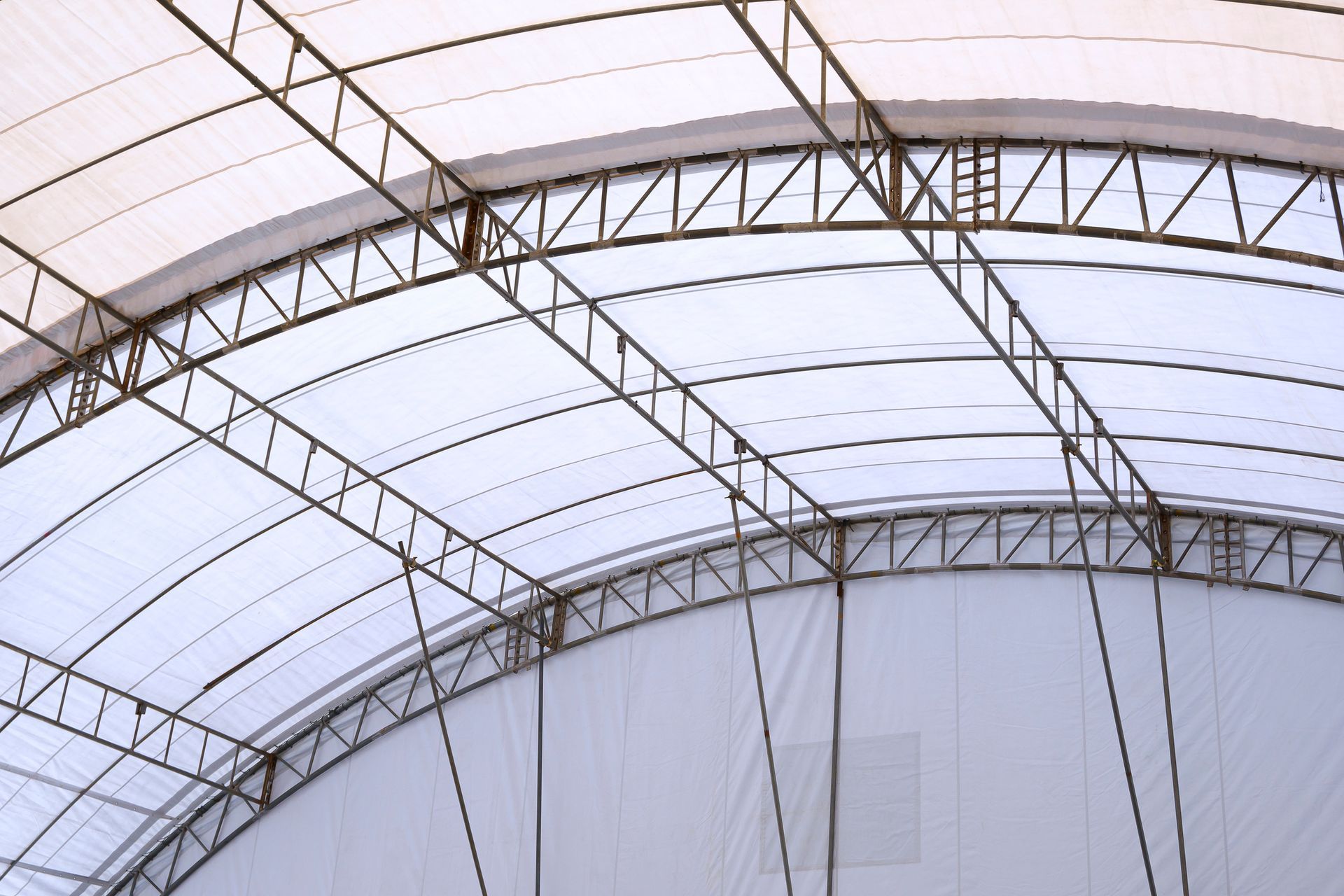 Curved white fabric roof supported by a metal truss structure.