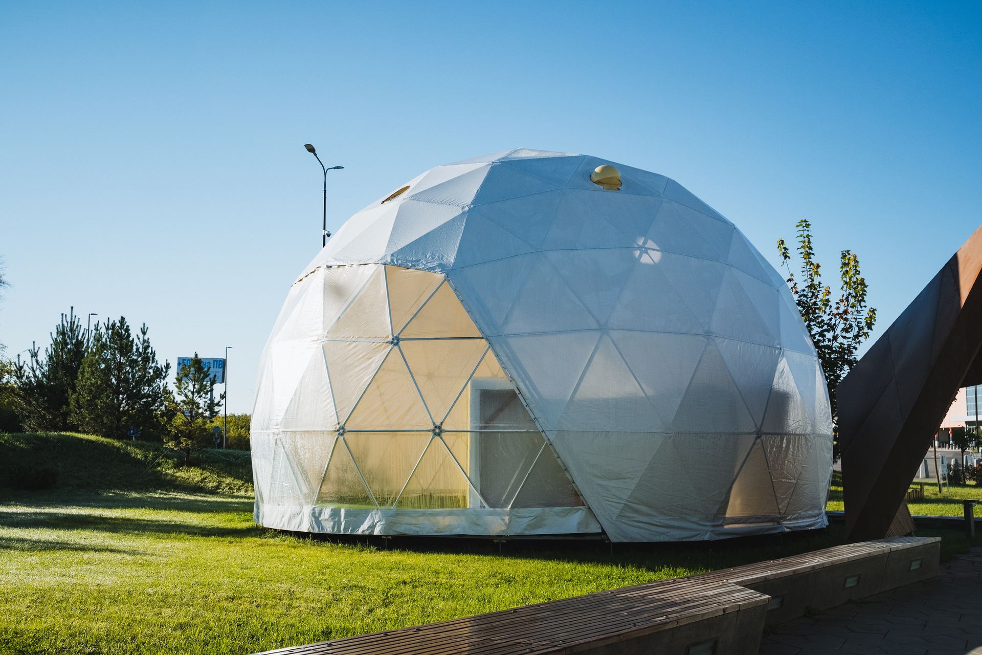 Geodesic dome structure on green grass under a clear blue sky.