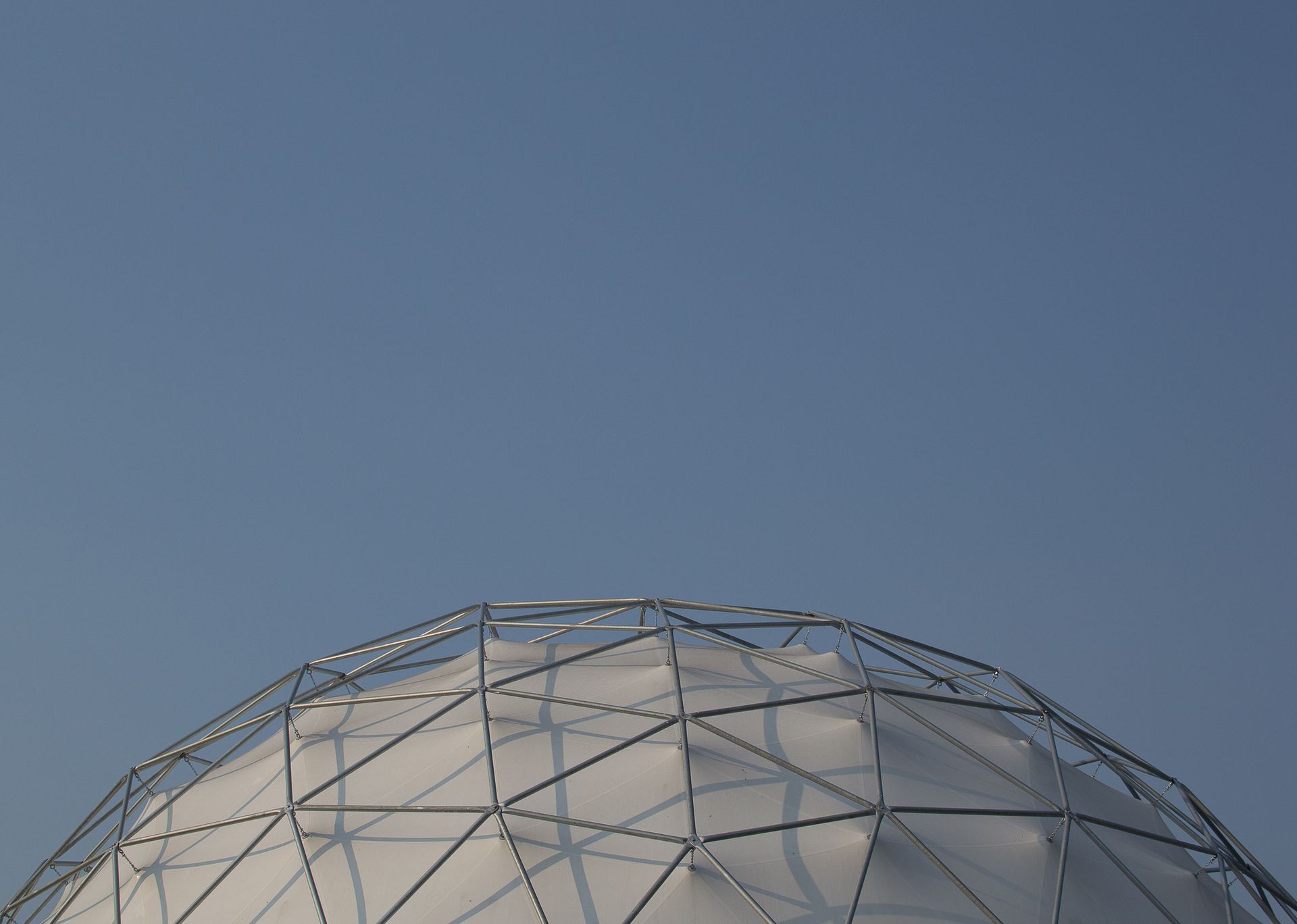 White geodesic dome structure against a clear blue sky.