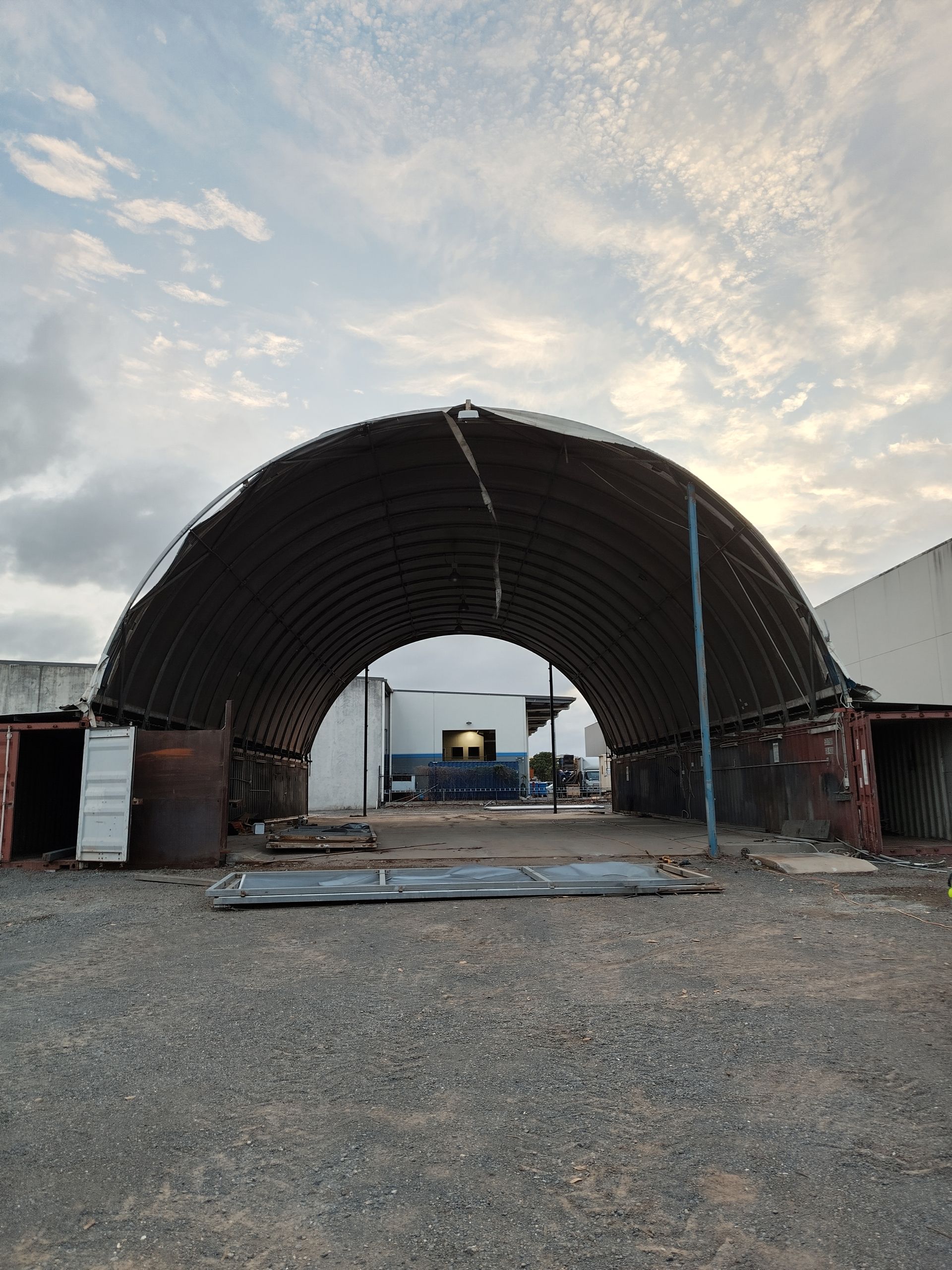 White arched building entrance with snow, trees in background.