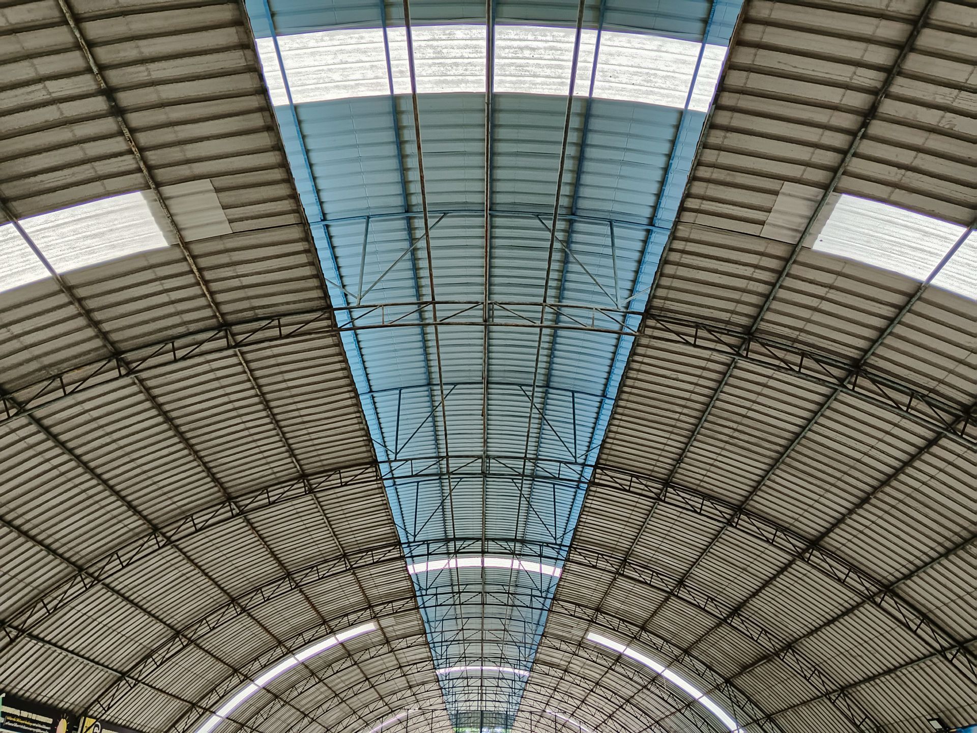 Arched metal roof of a building with blue and white translucent panels for natural light.