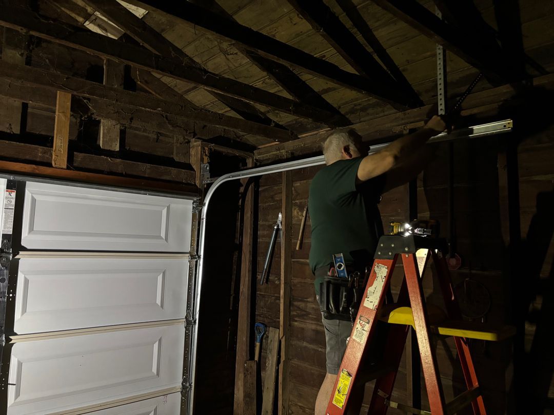 A man is working on installation of a garage door.