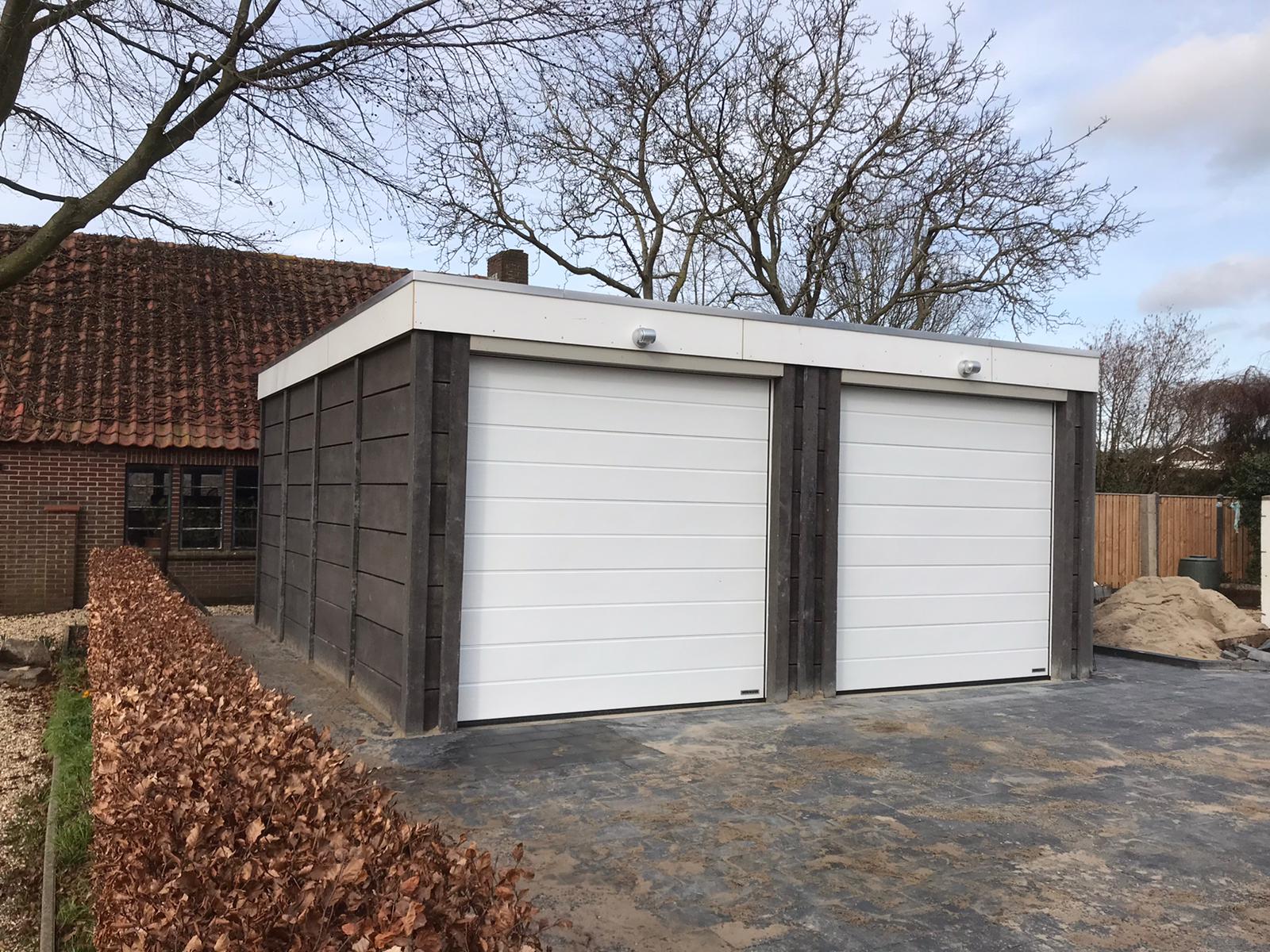 Dubbele betonnen garage met witte deuren en donkergrijze panelen, gebouwd door A&B Betonbouw.