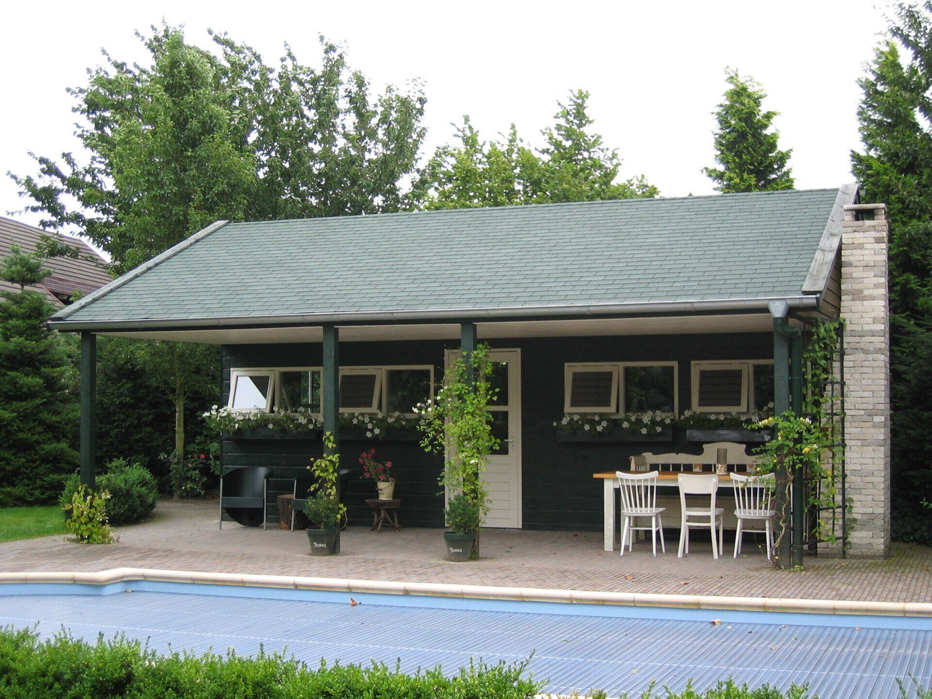 Tuinhuis met veranda en groene dakbedekking, duurzaam ontwerp van A&B Betonbouw.