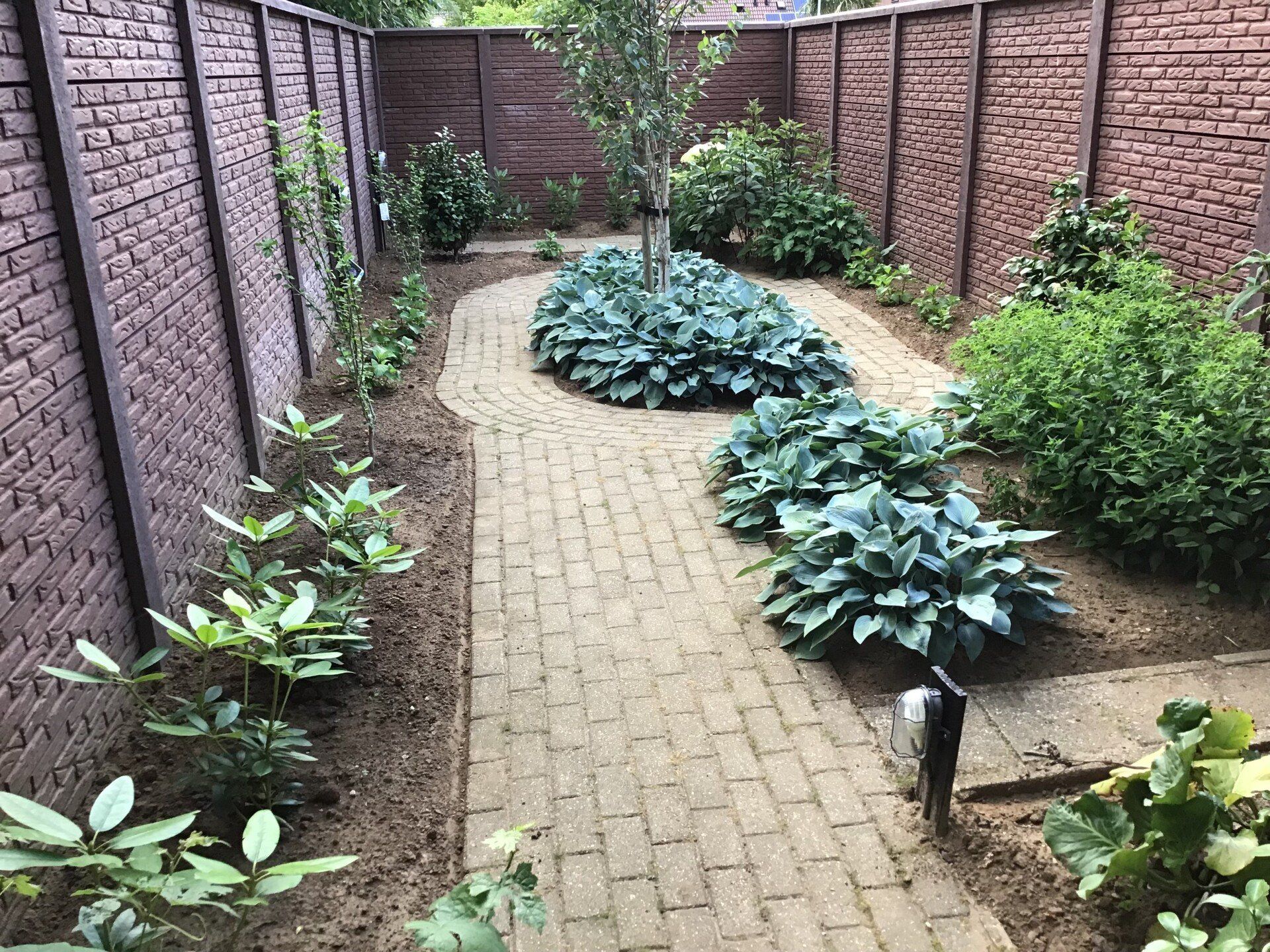 Tuin met betonschutting in handvormsteenmotief en bruine kleur, geplaatst door A&B Betonbouw.