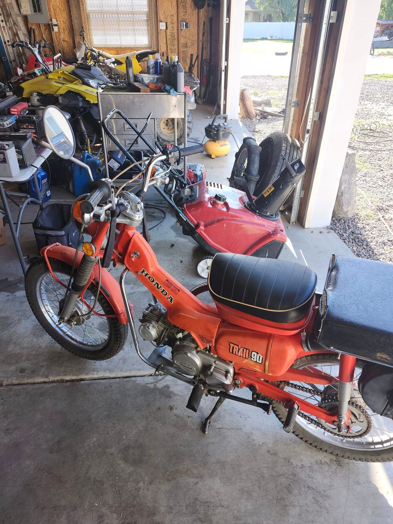 Orange Honda Trail 70 motorcycle parked in a garage.
