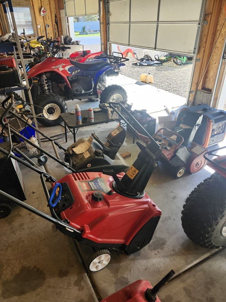 Red snowblower in a garage, with an ATV and other equipment.