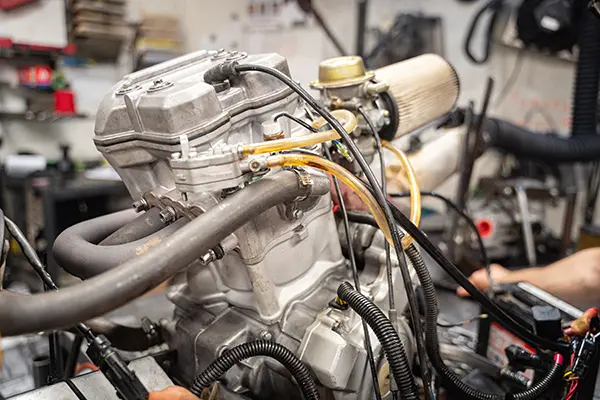 Engine with air filter, tubing, and wiring in a workshop setting.