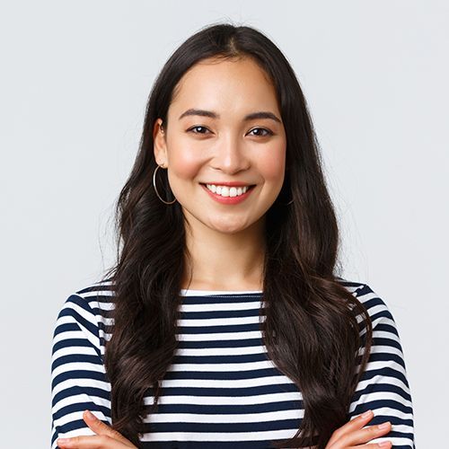 A woman in a striped shirt is smiling with her arms crossed.