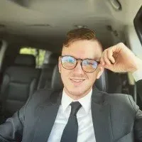 A man in a suit and tie is sitting in the back seat of a car.