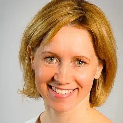 A woman with short blonde hair is smiling for the camera.