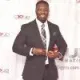 A man in a suit and tie is standing in front of a white wall.