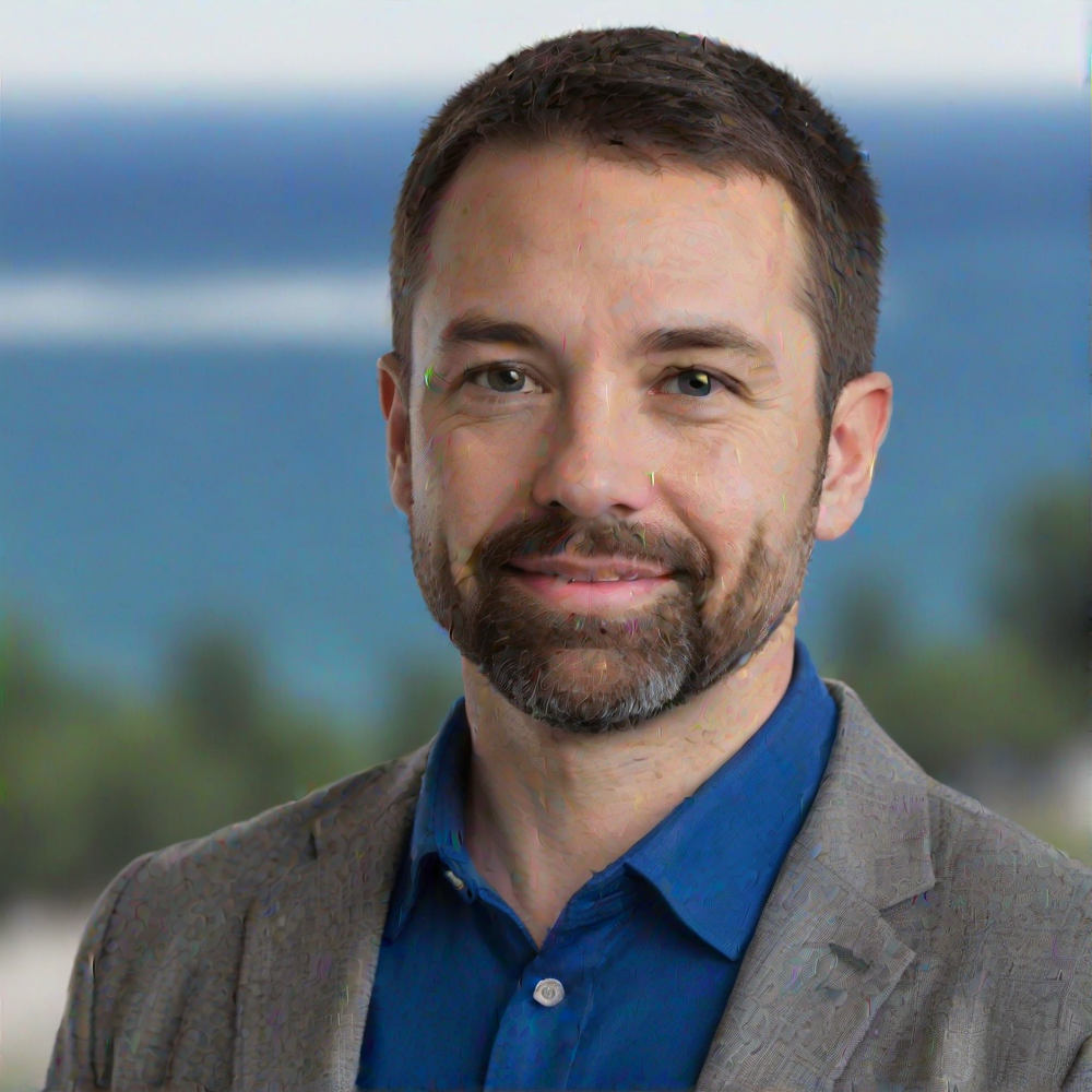 A man in a blue shirt and tie is smiling for the camera.