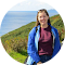 A woman in a blue jacket is standing in front of a hill.