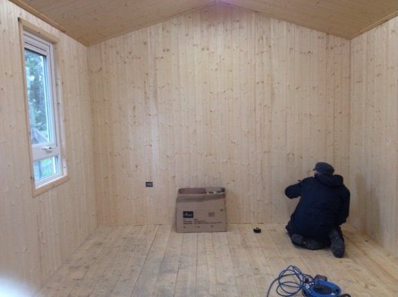 Man putting the finishing touches to the inside of a Summer house