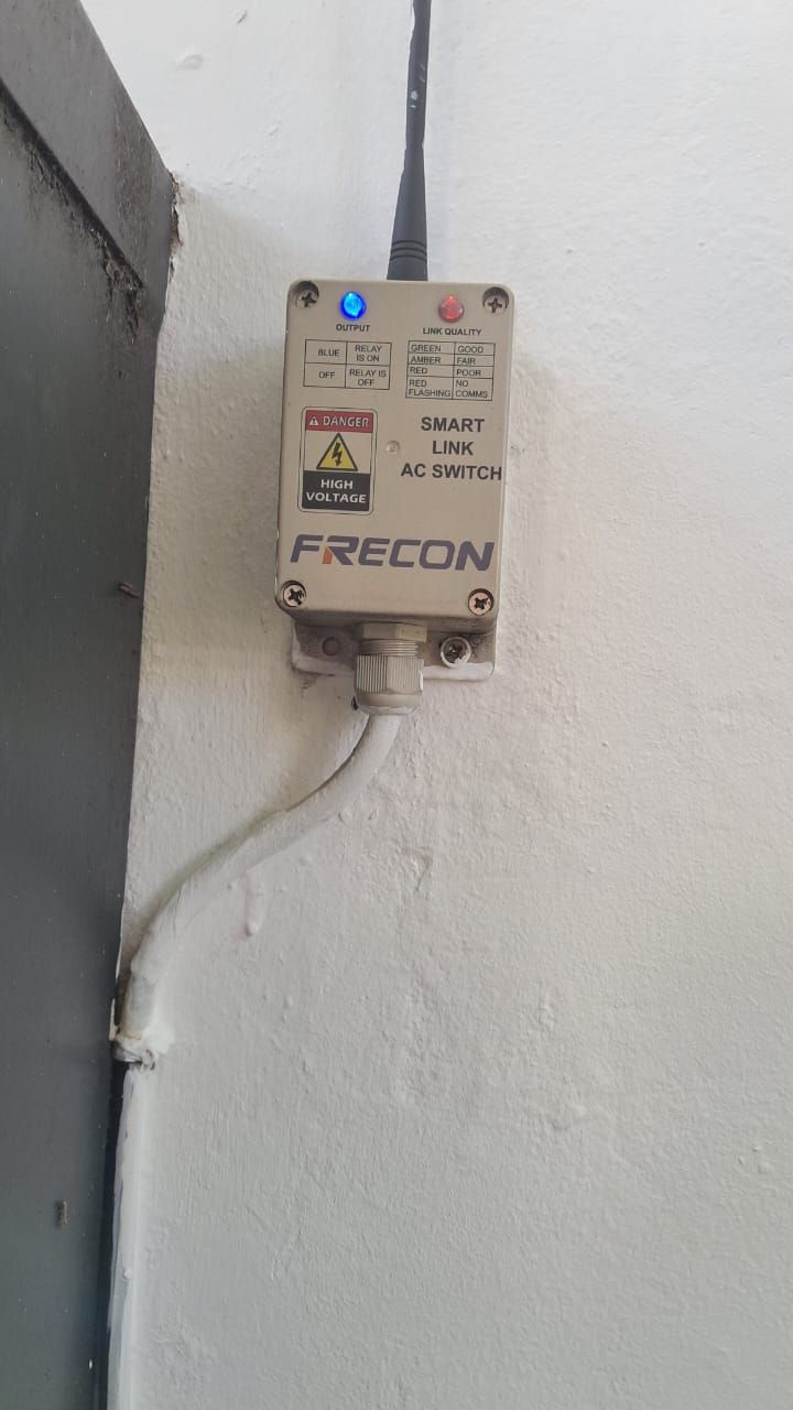 A box with a blue light on it is hanging on a wall.