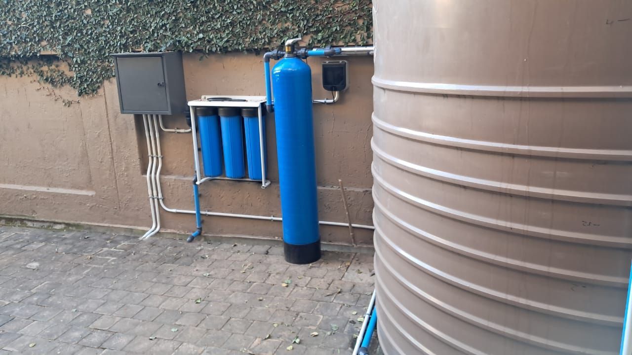 A blue water filter is sitting next to a brown water tank.