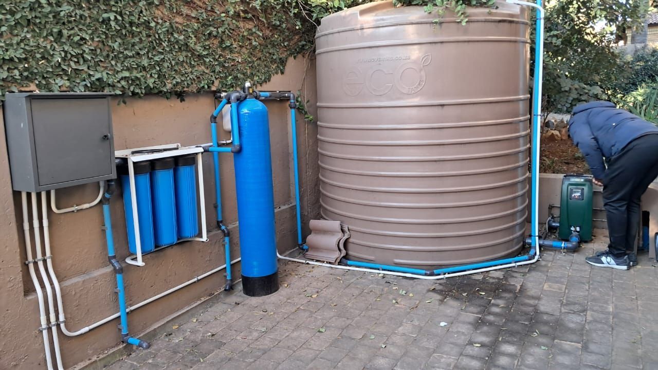 A man is standing in front of a water tank.