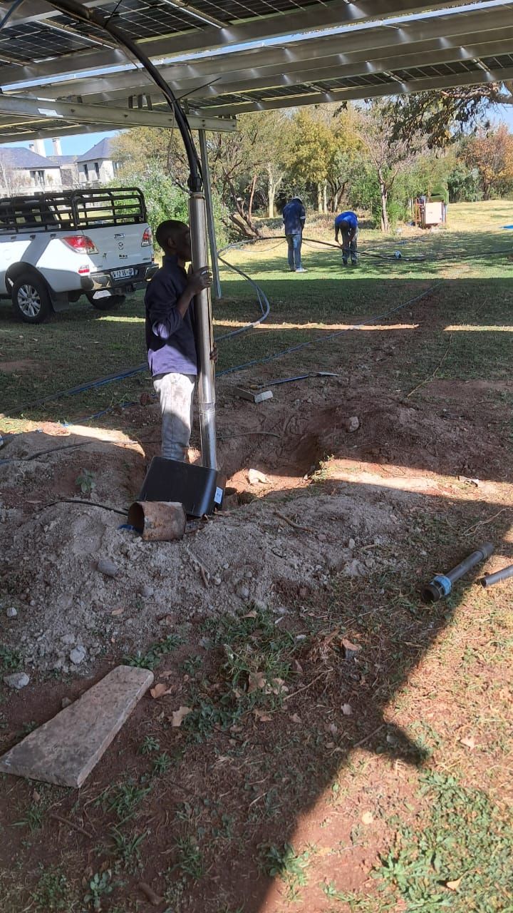 A man is standing in a dirt field holding a pole.