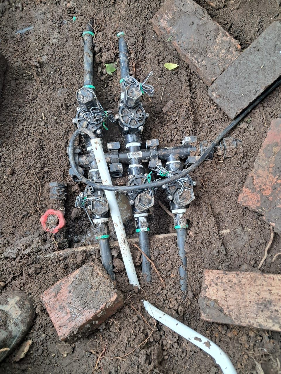 A bunch of pipes are laying in the dirt on the ground.