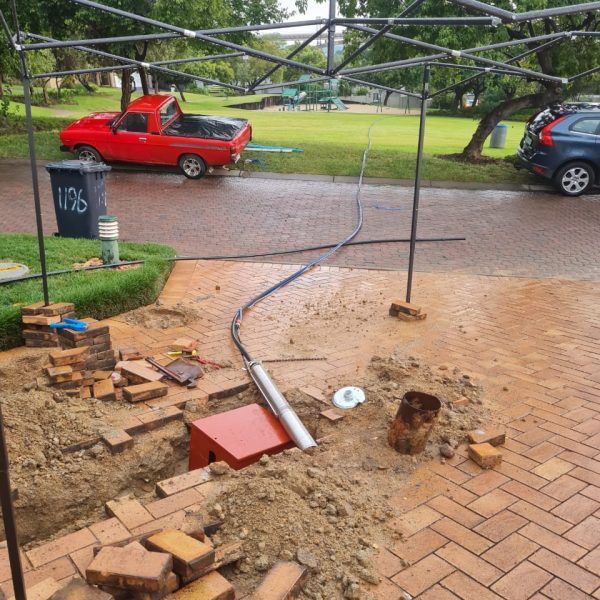 A red truck is parked next to a trash can with the number 76 on it