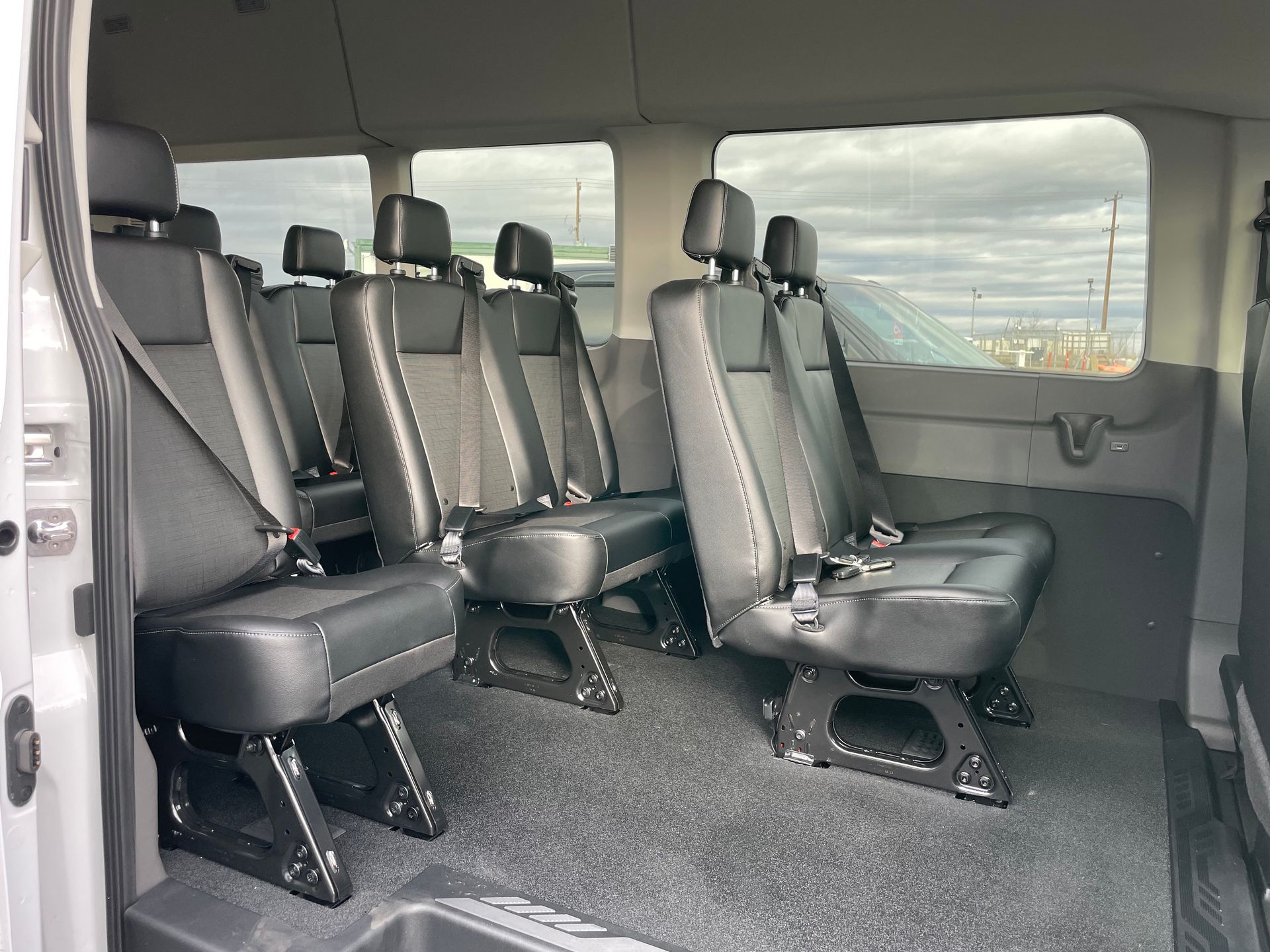the inside of a white 13 passenger executive shuttle van with black seats