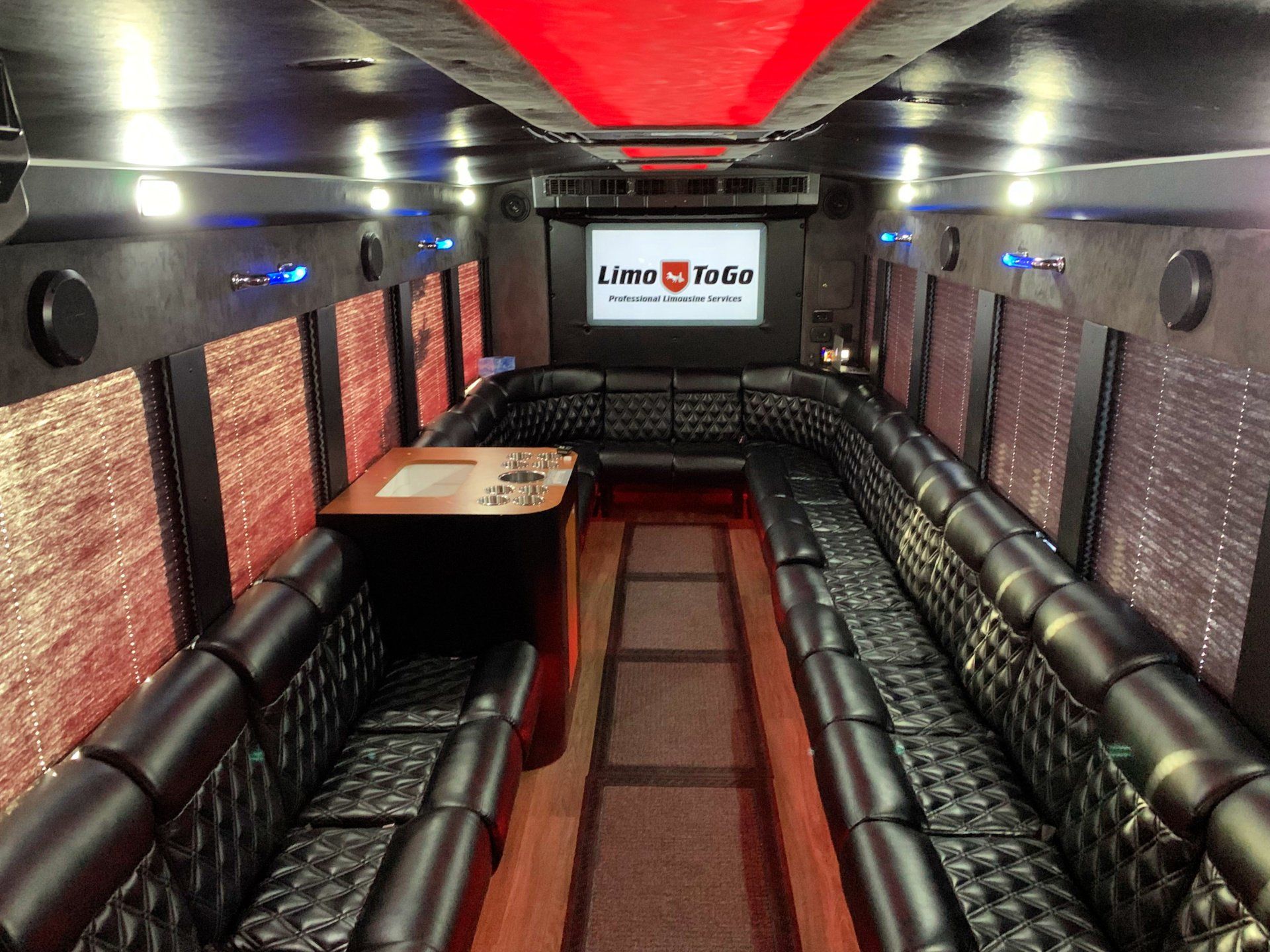 The inside of a limo ride bus with a projector screen.