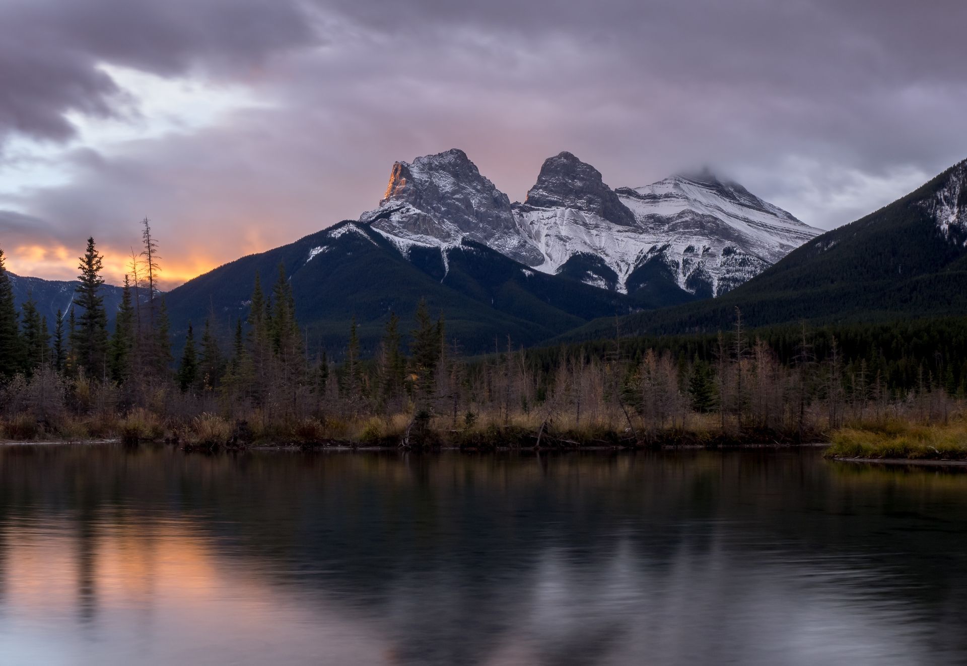 A lake with mountains in the background and trees on the shore.