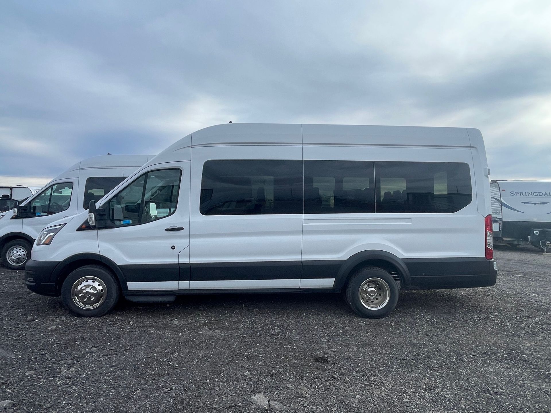 A white van is parked in a gravel lot.