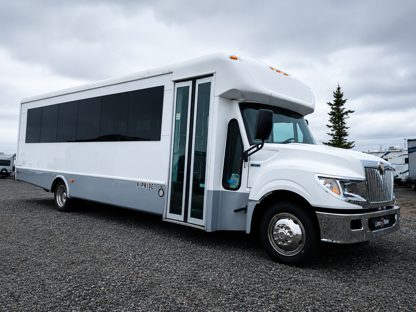 White shuttle bus parked on gravel under an overcast sky