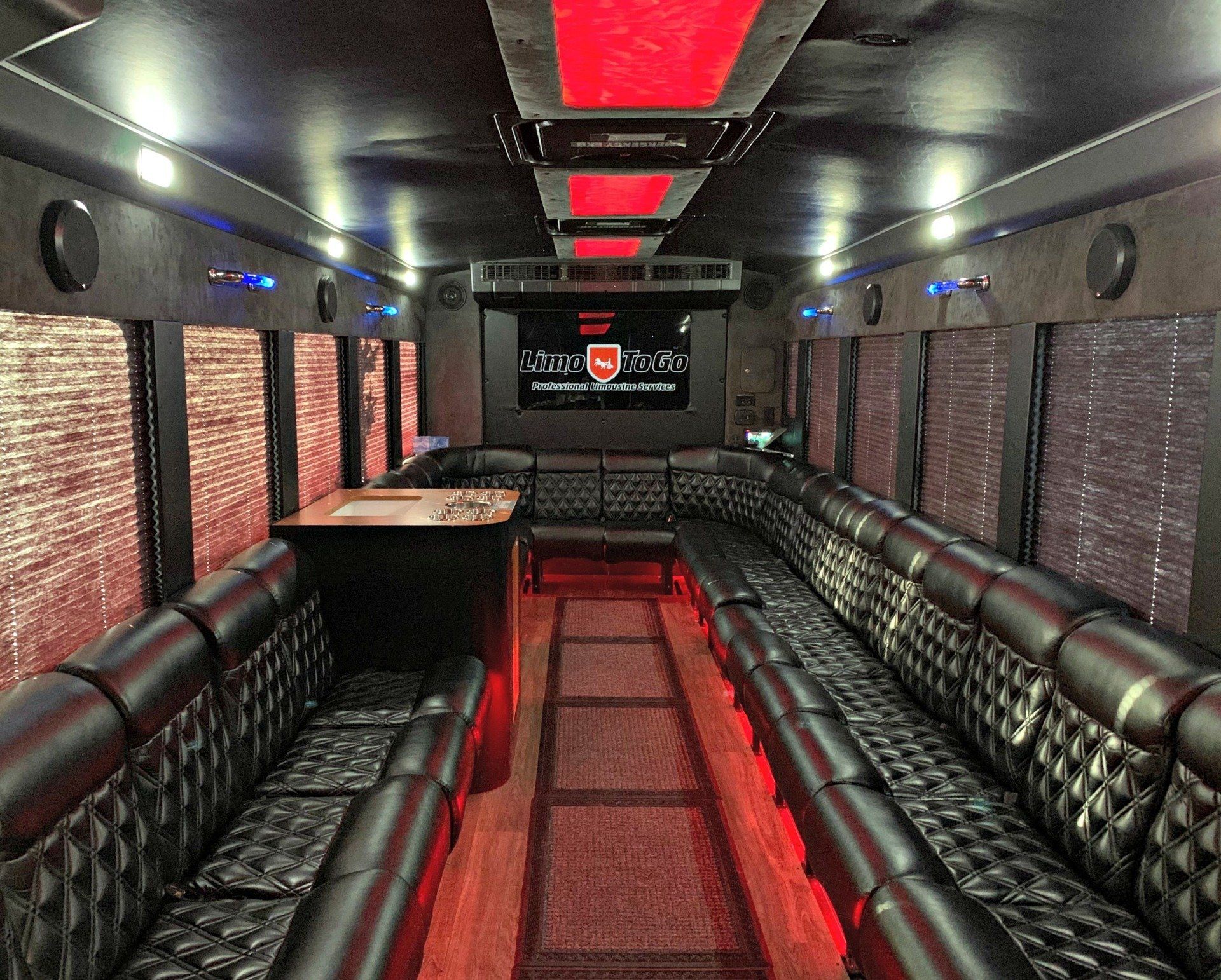 2014 International party bus red led lighting interior view with black Limo To Go logo on big screen tv