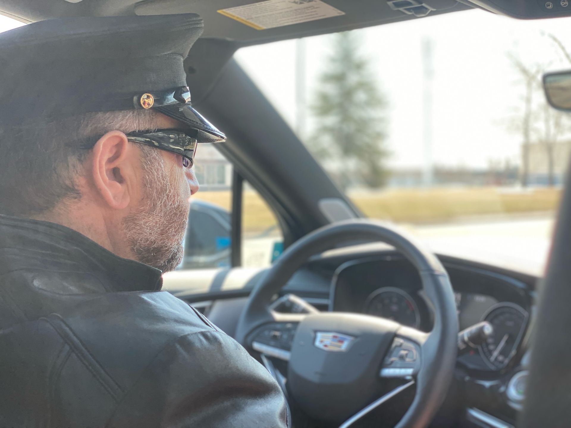 A man wearing a hat and sunglasses is driving a car.