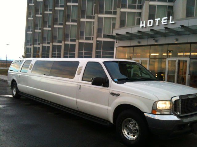 A white limousine is parked in front of a hotel