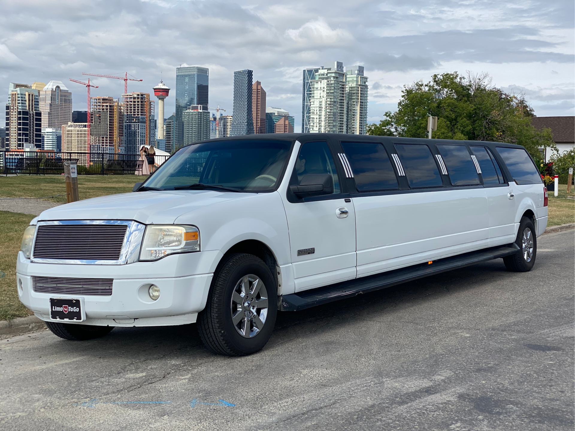 Tuxedo style stretch SUV limousine parked with city skyline in background