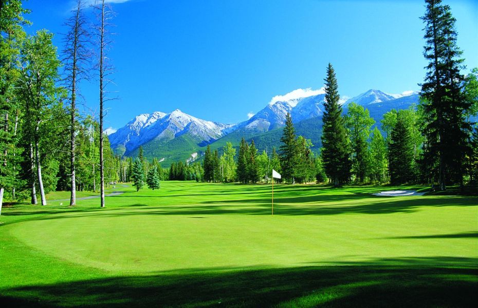 a golf course with mountains in the background and trees in the foreground