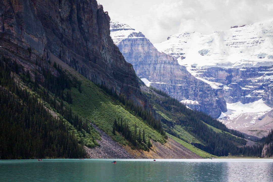 A lake surrounded by mountains and trees with a mountain in the background.