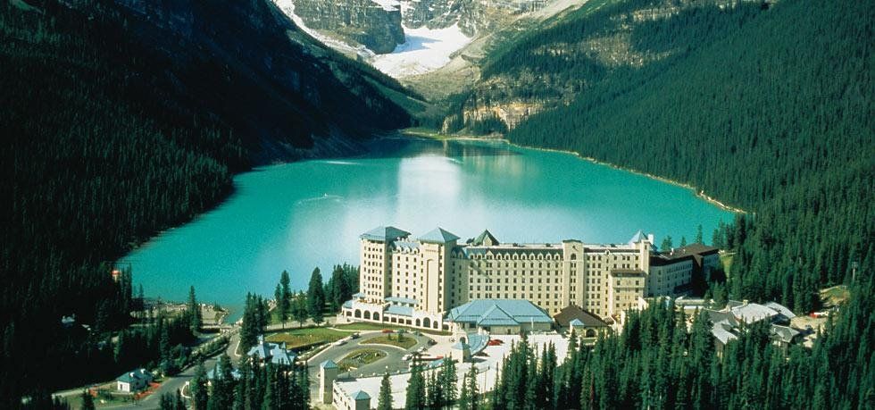 An aerial view of a lake surrounded by mountains and trees