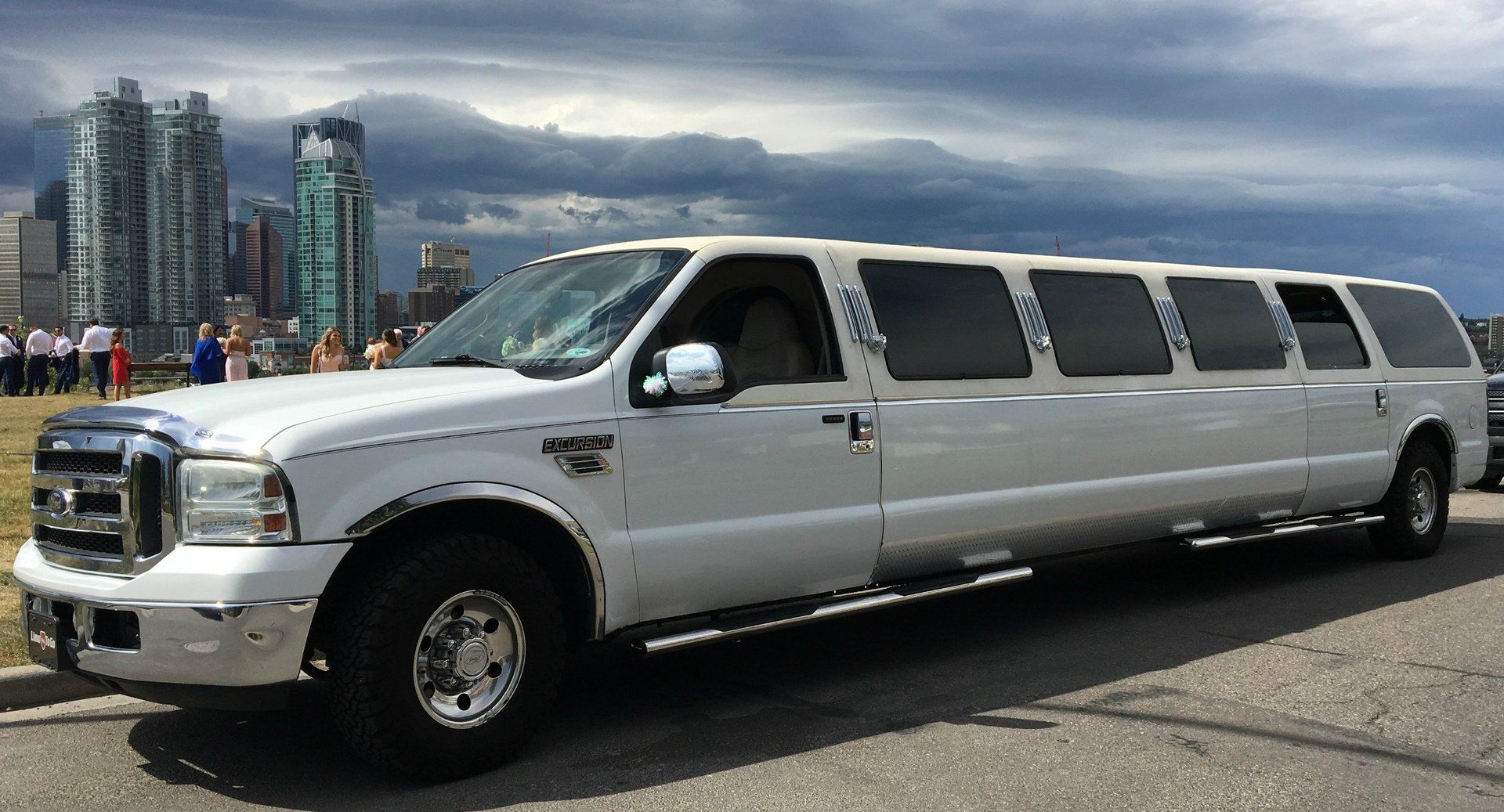 white Excursion stretch SUV limousine with city of Calgary skyline in background